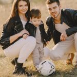 A family enjoys a warm day bonding and playing soccer outdoors in the park.