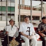 Group of seniors sitting together on a bench, enjoying a relaxed moment in an urban setting.